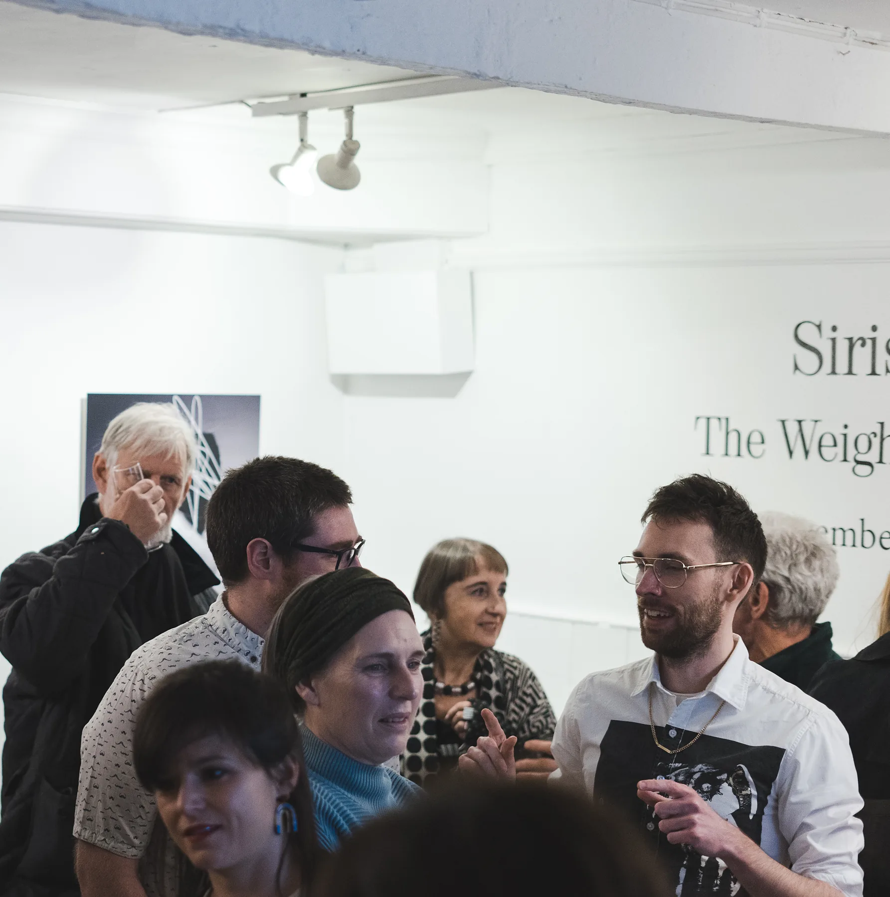 Visitors at the opening beneath the exhibition title