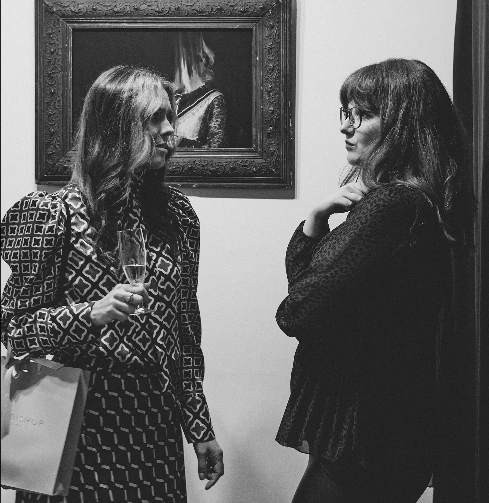 Two visitors in conversation beneath a painting