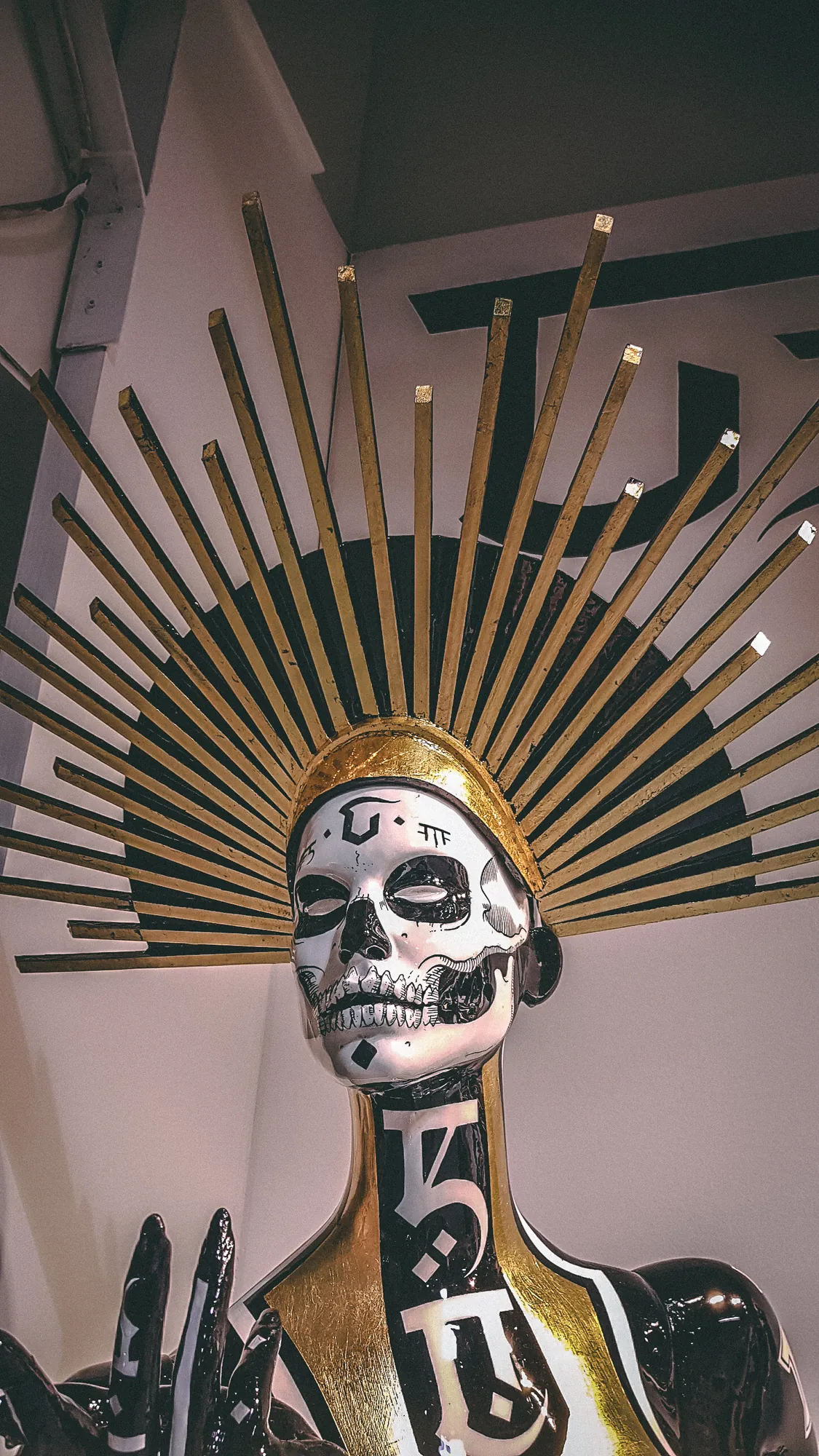 Detail of a sculptural skull artwork with a radiating gold crown